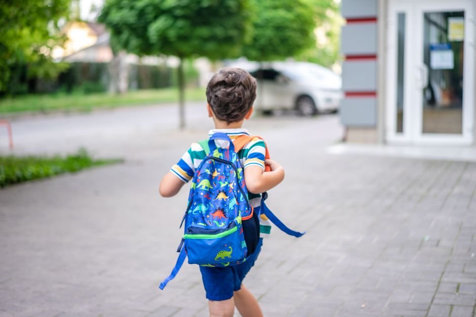 A child with a backpack walking into school