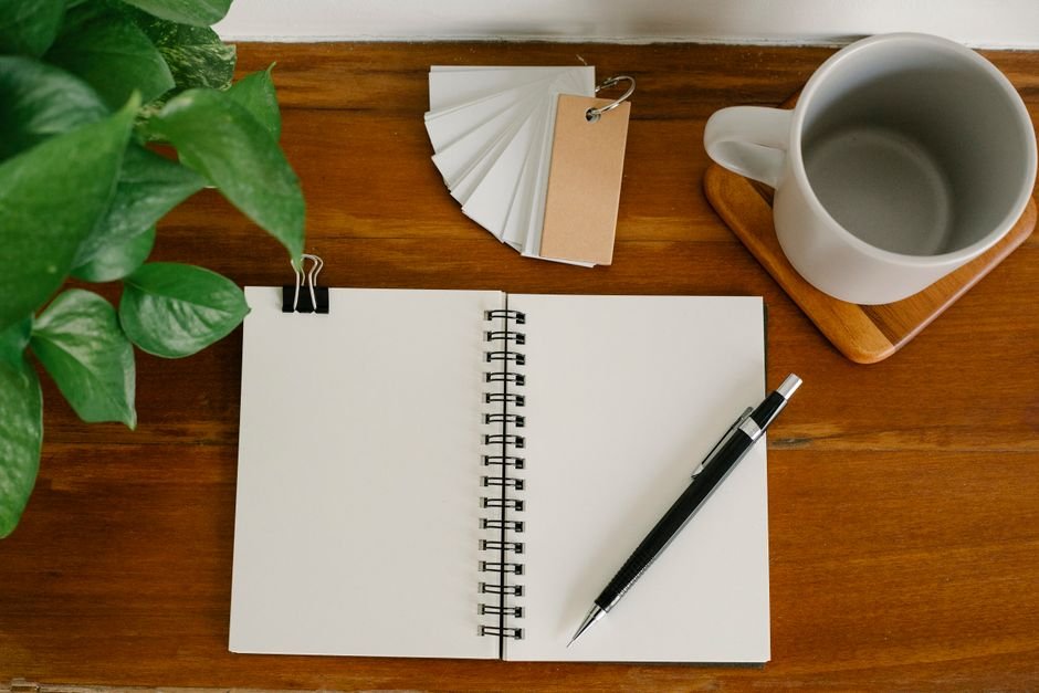 An open notebook and coffee cup on a wooden table